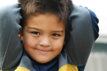 A boy smiling with his hands behind his head