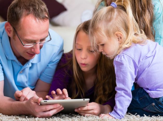 A man with daughters, using a tablet