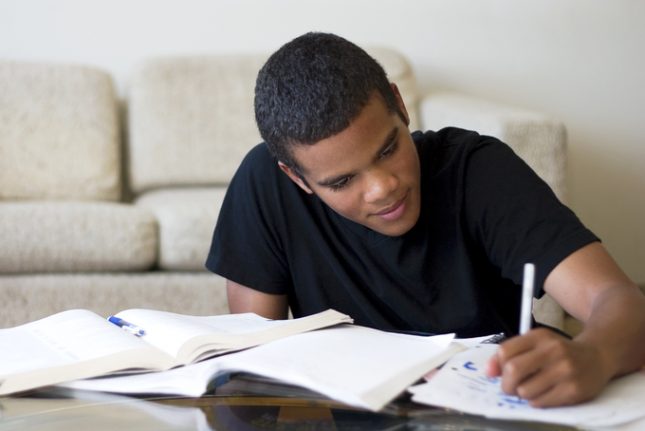 Teen doing homework on a coffee table