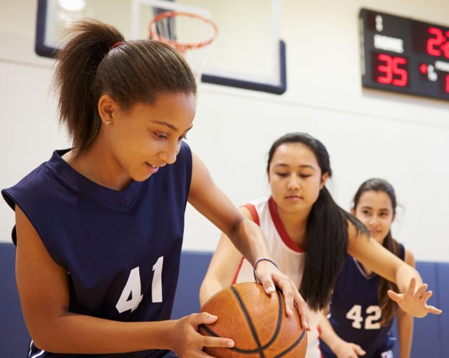 Teenage female basketball game in high school gym