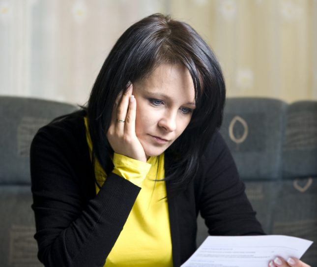 Woman sitting at a table, looking at an application form